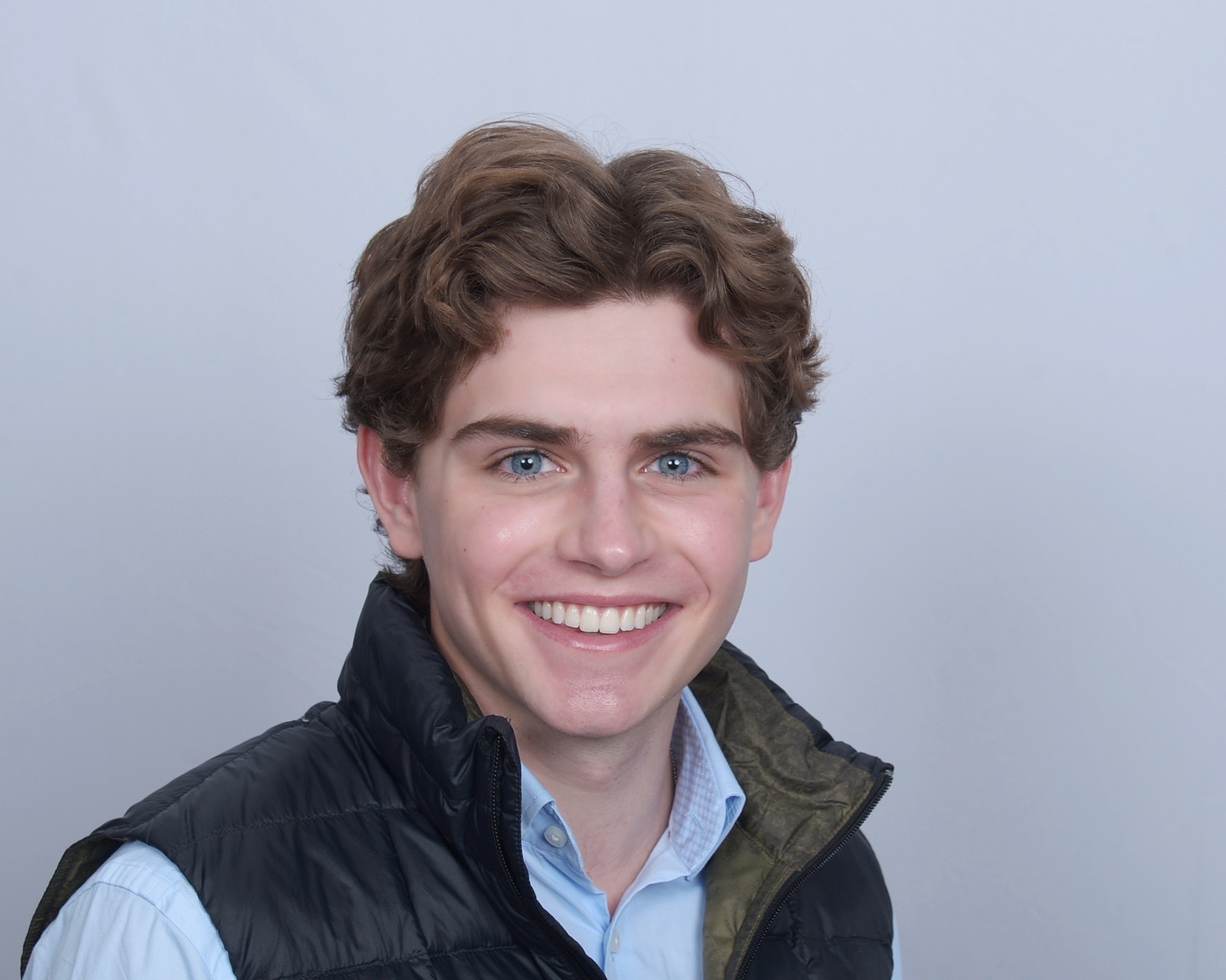 Ben Mackert smiling in a blue shirt and black vest